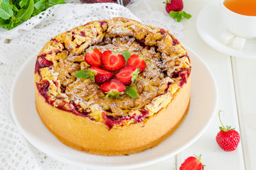 Baked creamy cheesecake with strawberries and crispy shtrezel on a plate on a white wooden...