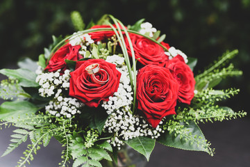 Wedding bouquet of red roses and wedding rings