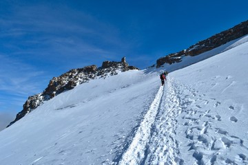 Fototapeta na wymiar Gran Paradiso National Park, Italy. Climbing to the summit of mount Gran Paradiso 4 061 m with cats and ice ax. Sunny chilly day.