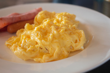 breakfast scrambled egg with ham and sausage on dish