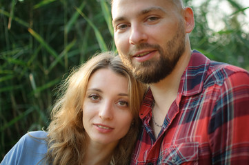 Fototapeta premium Close up portrait of young couple hugging and looking at the camera on green stems background, hipsters concept