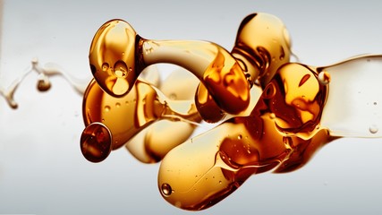 transparent orange gold oil bubbles and fluid shapes in purified water on a white gradient...