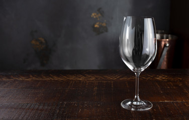 A wine glass is set on a rustic wooden table in a fine dining restaurant setting.