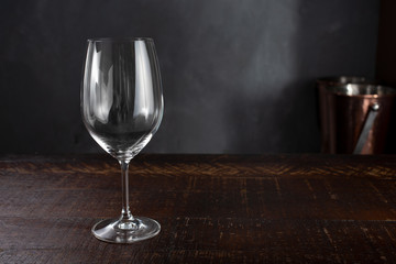 A wine glass is set on a rustic wooden table in a fine dining restaurant setting.