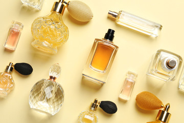 Flat lay composition with different perfume bottles on light yellow background