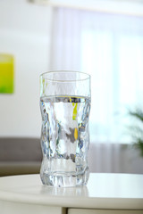 Glass of water on table in room. Refreshing drink