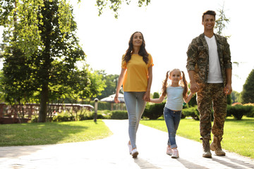 Man in military uniform and his family walking at sunny park