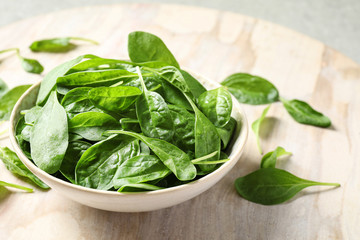 Bowl of fresh green healthy spinach on table