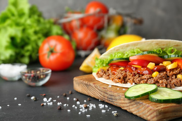 Delicious tortilla with meat and vegetables on dark table. Space for text
