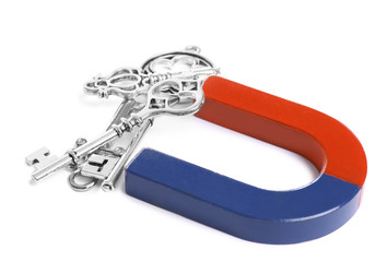 Horseshoe magnet attracting keys on white background