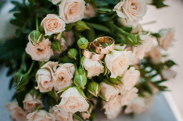 Gold wedding rings on the pink bouquet of flowers