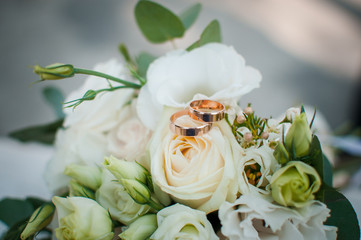 Fototapeta premium Gold wedding rings on the pink bouquet of flowers