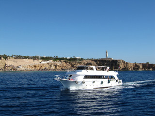 White boat sailing along the rocks on the red sea.