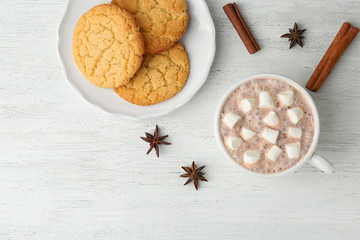 Composition with delicious hot cocoa drink and cookies on white wooden background, flat lay