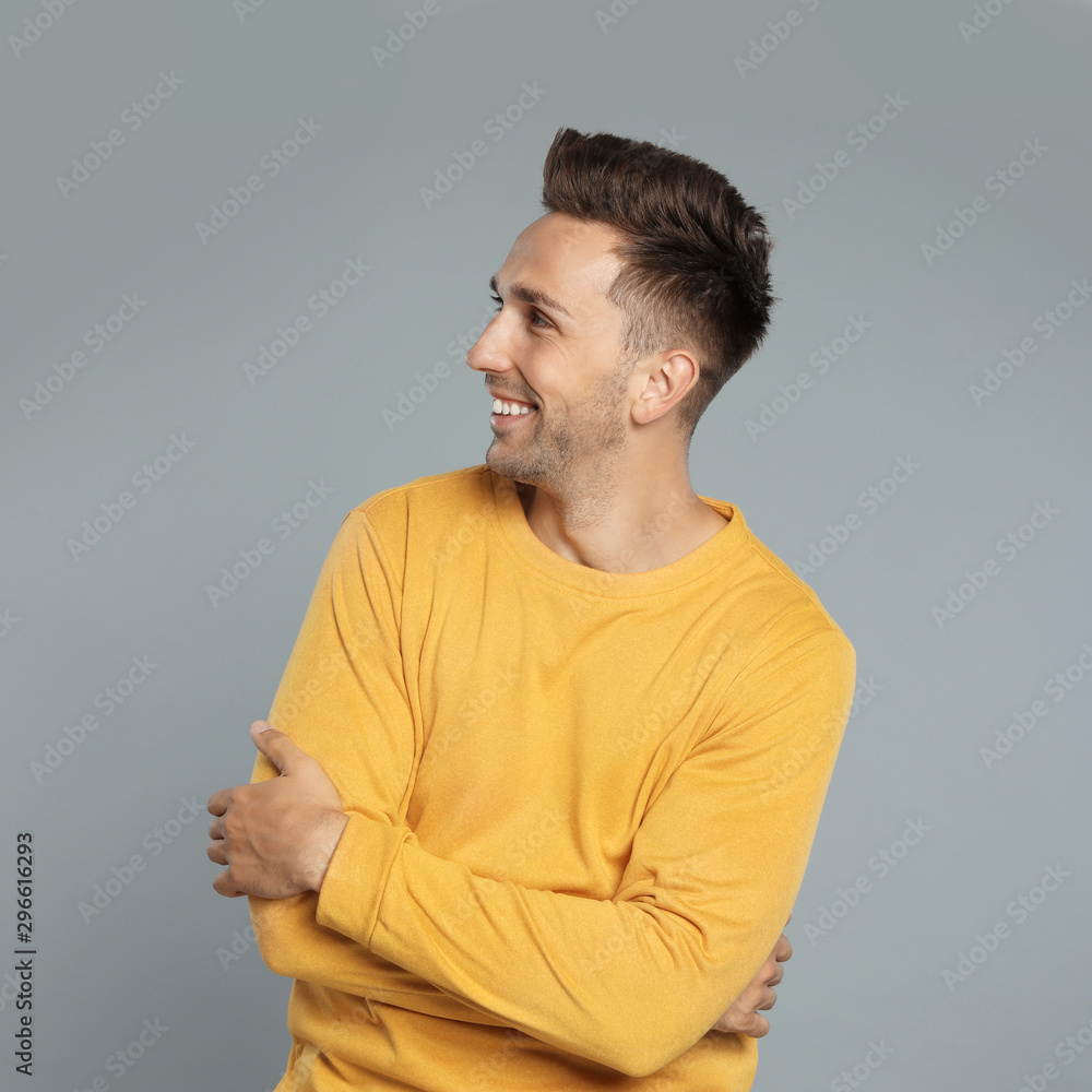 Wall mural Happy young man in yellow sweatshirt on grey background. Winter season