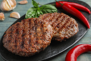 Grilled meat cutlets for burger on blue wooden table, closeup