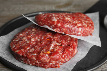 Raw meat cutlets for burger on wooden table, closeup