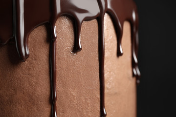 Freshly made delicious chocolate cake against black background, closeup