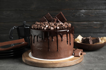 Freshly made delicious chocolate cake on grey table against black background