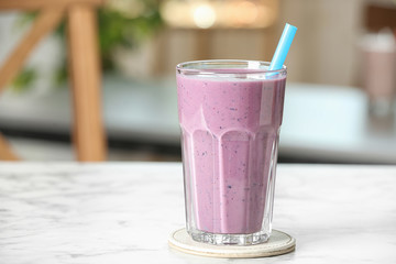 Tasty milk shake on white marble table indoors