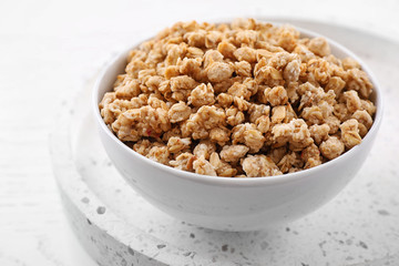 Bowl with healthy granola on white table, closeup