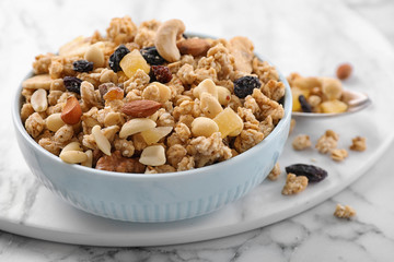 Bowl with healthy granola on white marble table, closeup