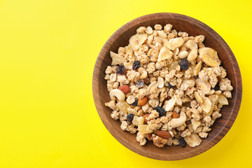 Bowl with healthy granola on yellow background, top view. Space for text