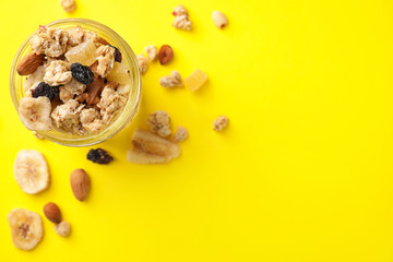 Jar with healthy granola on yellow background, flat lay. Space for text