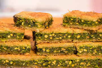 Close up of traditional oriental sweet pastry cookies known as kanafeh, Turkish desert with sugar, honey and pistachio,  in display at a street food market, top view