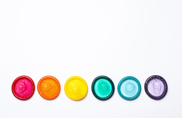 Colorful condoms on white background, top view. LGBT concept