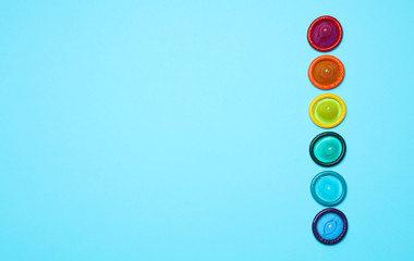 Colorful condoms on light blue background, flat lay. LGBT concept
