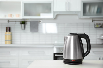 Modern electric kettle on wooden table in kitchen. Space for text