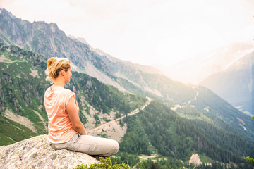 Woman sitting on a rock on top of the hill, watching panorama