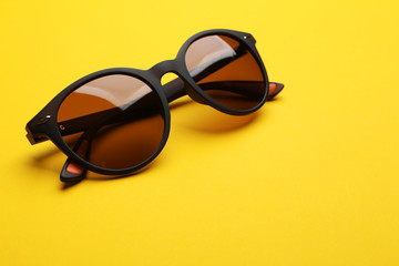 Stylish sunglasses on yellow background. Fashionable accessory