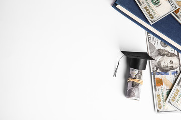 Flat lay composition with dollar banknotes and student graduation hat on white background, space for text. Tuition fees concept