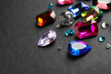 Different beautiful gemstones on black background. Space for text