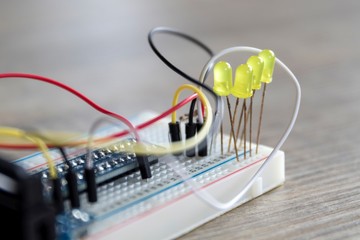 A portrait of an electronic circuit of LEDS on a breadboard with wires all around them and wired to a connection PCB of a raspberry pi. - obrazy, fototapety, plakaty