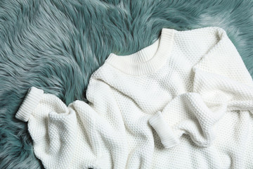 White knitted sweater on green fur rug, flat lay