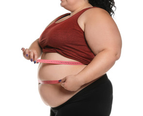 Overweight woman measuring waist with tape on white background, closeup