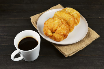 coffee cup and fresh baked croissants on wooden table