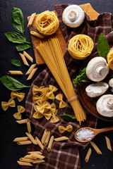 ingredients for cooking traditional pasta with mushrooms on dark stone background Top view Vertical.