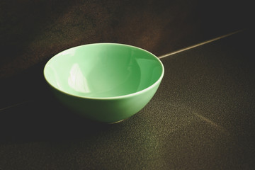 A dish of neo mint color on the dark background. Reflects light and shadow.