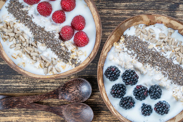 Smoothie in coconut bowl with blackberries, raspberries, oatmeal, sunflower seeds and chia seeds for breakfast , close up. The concept of healthy eating, superfood