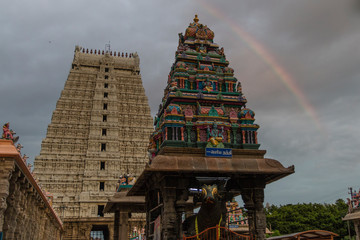 entrance tower and an inside monument of the Annamalaiyar temple of Tiruvannamalai, Tamil Nadu, being one of the biggest temple in south India in summer 2019 at sunset with rainbow in background