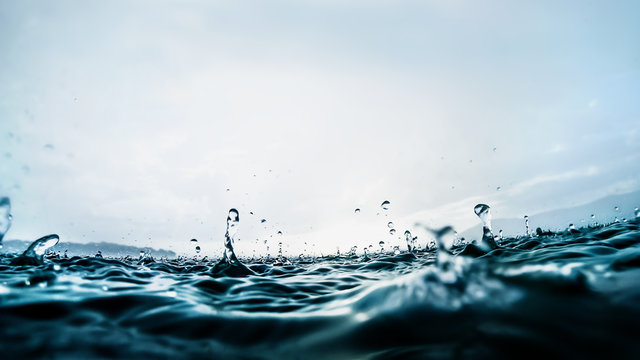 Raindrops splashing into dark blue lake