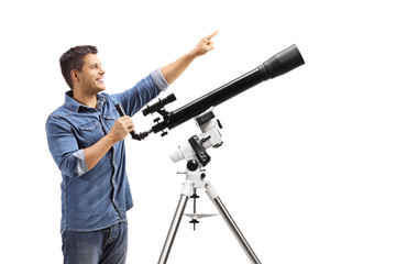 Youn man standing next to a telescope and pointing up