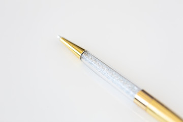 Macro photo of gold and crystal pen on white background
