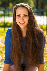 Young beautiful brunette woman in blue dress in autumn park