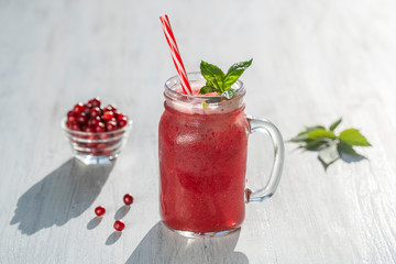 Fresh organic red smoothie in glass mug on white table, close up. Refreshing summer fruit drink. The concept of healthy eating. Cranberry and raspberry smoothie