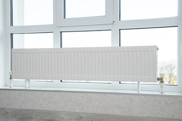 Heating radiator in front of window at an apartment.